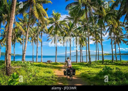 Ciclista solitario che viaggiano attraverso la giungla indonesiana in isola di Sumbawa in Indonesia in Asia Foto Stock