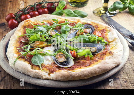 Cozza la pizza con il razzo su una piastra per pizza Foto stock - Alamy