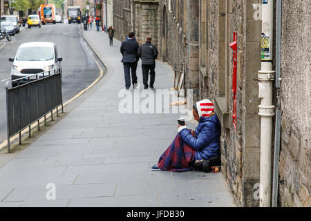 Edinburgh, Regno Unito: Maggio 26, 2016: un mendicante femmina si trova su una strada trafficata di Edimburgo. Ella è in possesso di una tazza di denaro e di essere ignorato dai passanti. Foto Stock