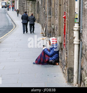 Edinburgh, Regno Unito: Maggio 26, 2016: un mendicante femmina si trova su una strada trafficata di Edimburgo. Ella è in possesso di una tazza di denaro e di essere ignorato dai passanti. Foto Stock