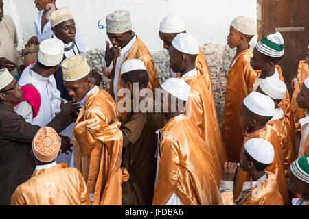 Gruppi di uomini e ragazzi celebrano il Zefe processione lungo le strette stradine della città vecchia di Lamu durante il festival Maulidi, Kenya, Africa Foto Stock