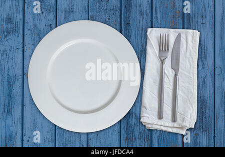 Piastra vuota con posate in legno blu vista dall'alto. Foto Stock