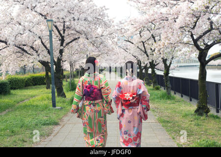 Coppia donne asiatiche indossando il tradizionale kimono giapponese Sakura nel giardino di Osaka in Giappone.