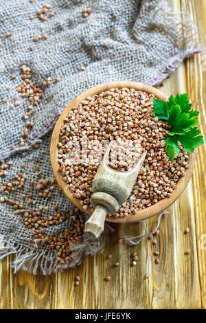 Cucchiaio di legno in una ciotola con il grano saraceno. Foto Stock