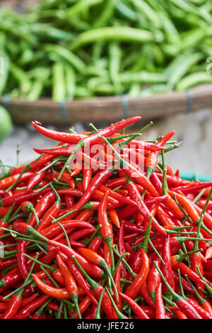 Freschi peperoncino rosso da vicino con i peperoni verdi in background blured. Gli ingredienti della cucina. Verticale. Foto Stock