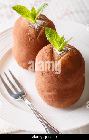 Rum tradizionale sfere la torta con la menta e cacao in polvere close-up su una piastra. In verticale Foto Stock