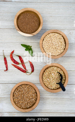 Bacche di grano saraceno Semole e semolini di orzo perlato Farrow in ciotole con peperoni rossi sul lato Foto Stock