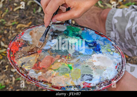 Il pittore si mescola i colori della verniciatura pannello per applicare l'immagine. Foto Stock
