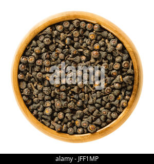 Essiccato cassia gemme nella ciotola di legno. Fiori non aperti della cassia tree, colti prima della fioritura. Cinnamomum cassia cassia cinese cinese o di cannella. Foto Stock