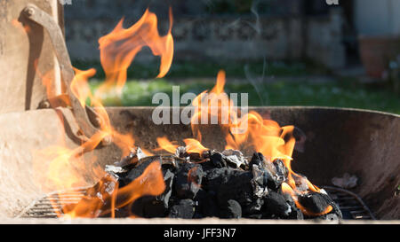 Le fiamme salire dal carbone che brucia su un barbecue in giardino Foto Stock