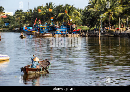 La donna in una barca a remi lookoing turistico per i clienti sul fiume Thu Bon in Hoi An, Vietnam Foto Stock