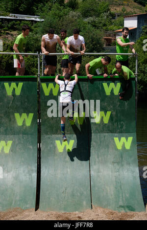 I concorrenti che si aiutano reciprocamente salire una parete durante una corsa a ostacoli gara Foto Stock