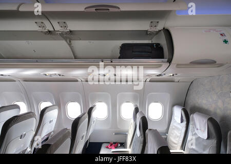 Valigia in scompartimento superiore di un vuoto aereo commerciale Foto Stock
