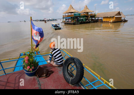 Barca accanto a un edificio su un villaggio galleggiante nelle acque del fiume Mekong, Cambogia Foto Stock