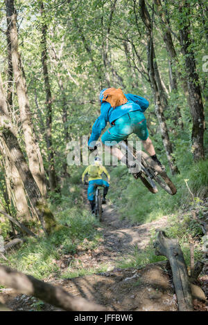 Biker jumping in metà di aria durante la guida bike e a seguito di altre biker sul percorso di sporcizia Foto Stock