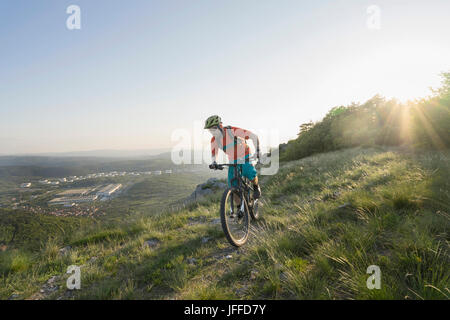 Uomo maturo equitazione mountain bike sulla collina Foto Stock