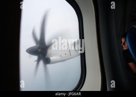 Persona guardando fuori dalla finestra di un aereo a elica motore Foto Stock