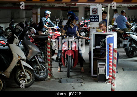 Donna di pagare per il parcheggio mentre cavalcate uno scooter per le strade della città di Ho Chi Minh in Vietnam, in Asia Foto Stock