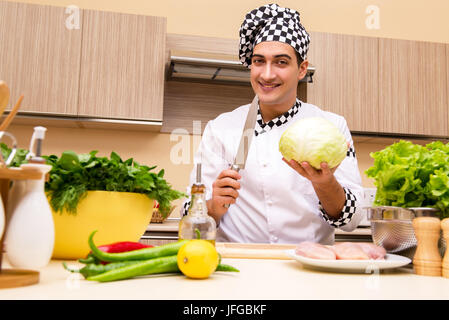 Il giovane chef lavorando in cucina Foto Stock