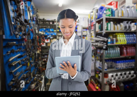 Immagine composita di imprenditrice utilizzando una compressa con i colleghi dietro Foto Stock