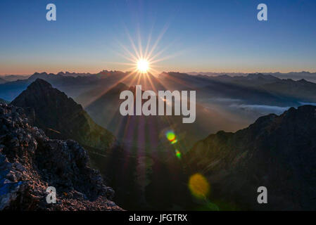 Sunrise e sunray oltre Karwendel con Arnspitzen nella terra di mezzo, primo piano gamma Wetterstein, vista del Schüsselkarspitze, Foto Stock