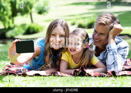 I genitori e la figlia di prendere una selfie sul telefono cellulare Foto Stock