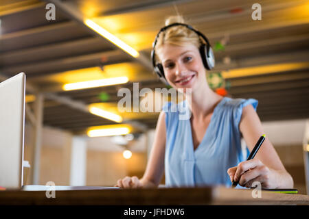 Graphic designer ascoltando le cuffie mentre con tavoletta grafica Foto Stock