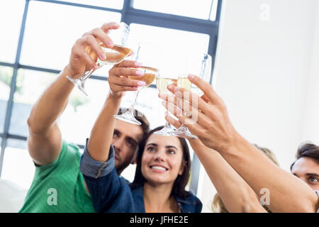 Sorridente amici seduti sul divano bicchieri tintinnanti Foto Stock