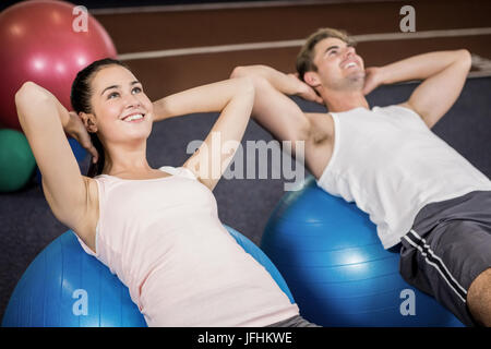 L uomo e la donna facendo sgranocchia addominale sulla sfera di fitness Foto Stock