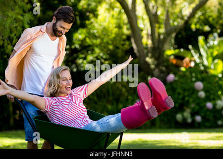 L'uomo spinge donna seduta in carriola in cantiere Foto Stock