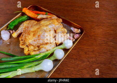 La cottura di pollo con ingredienti - carote, erbe aromatiche e spezie prima della cottura in forno. Sfondo scuro per un menu Libro di ricette o design. Home destinatario Foto Stock