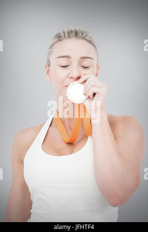 Immagine composita di felice atleta femminile kissing medaglia Foto Stock