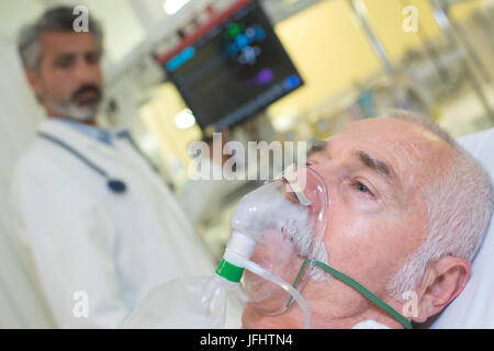 Medico guardando il paziente che indossa la maschera di ossigeno Foto Stock