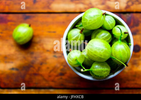 Una piccola ciotola di uva spina in grigio la coppa in ceramica, la coppa è piena di uva spina, ci sono 5 verde uva spina sulla parte superiore della vaschetta, la ciotola di Foto Stock