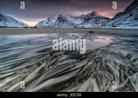 Onde il surreale Skagsanden spiaggia circondata da montagne coperte di neve, Isole Lofoten in Norvegia, Europa Foto Stock