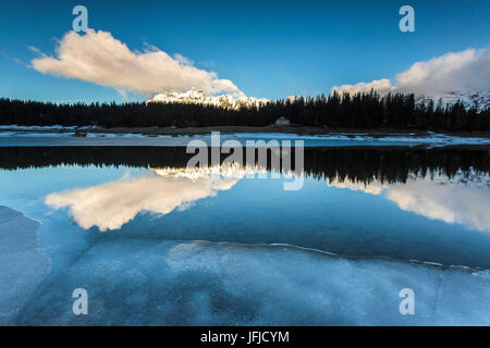 La molla del disgelo si scioglie il ghiaccio mentre vette innevate sono riflesse nel lago Palù Sondrio Malenco Valley Valtellina Lombardia Italia Europa Foto Stock