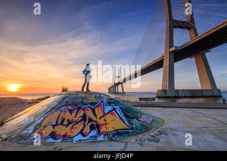 Un turista si ammira il maestoso Ponte Vasco da Gama sul Fiume Tagus Parque das Nações Lisbona Portogallo Europa Foto Stock