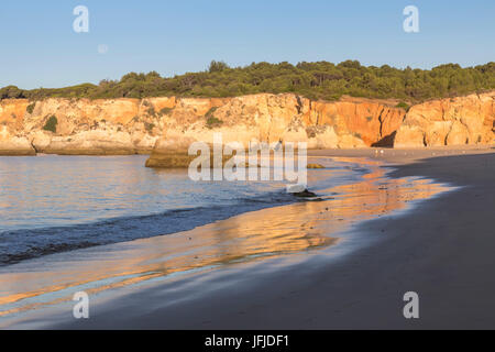 Il recentemente salito sole splende su scogliere e riflessa sulla spiaggia di Praia do Vau Algarve Faro District Portimao portogallo Europa Foto Stock