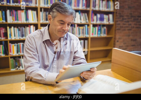 Il Professor seduto alla scrivania con tavoletta digitale Foto Stock
