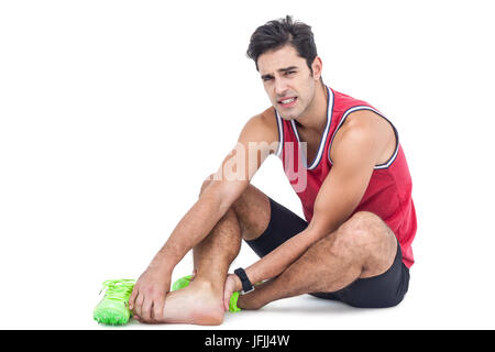 Ritratto di atleta maschio con dolore del piede su sfondo bianco Foto Stock