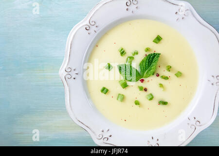 Un ingrandimento di foto aeree di vichyssoise, un francese di patate e porri minestra con cipollotti tritati, grani di pepe rosa e le foglie di menta per la decorazione Foto Stock