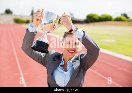 Ritratto di felice imprenditrice tenendo in mano un trofeo Foto Stock