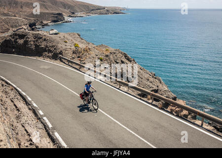 Mountain biker in sella della bicicletta elettrica su strada per mare Foto Stock