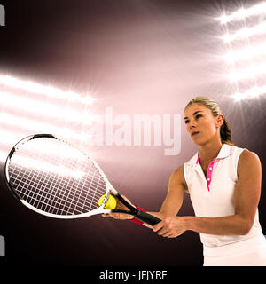 Atleta giocando a tennis con un racket contro spotlight Foto Stock