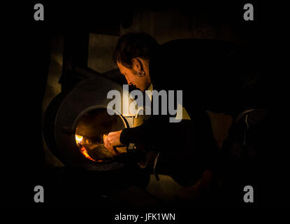 Uomo maturo mettendo il legno in forno Foto Stock