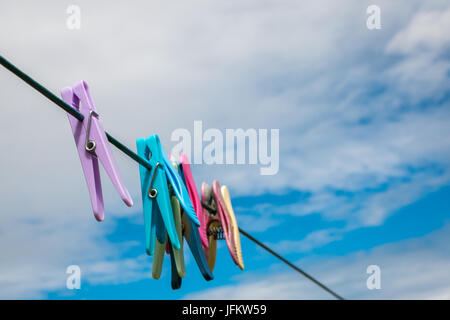 Close up di abbigliamento colorato pioli su una linea di lavaggio contro il cielo Foto Stock