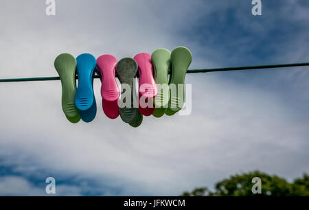 Close up di abbigliamento colorato pioli su una linea di lavaggio contro il cielo Foto Stock