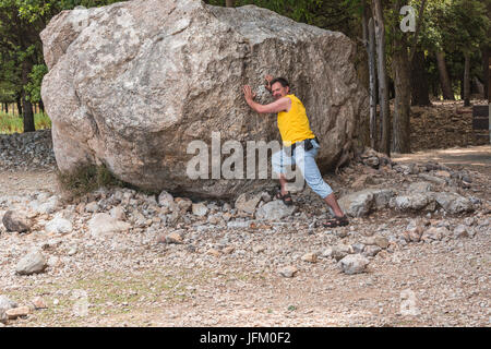 L uomo sta di fronte ad una grande roccia. Compito Cope. Foto Stock