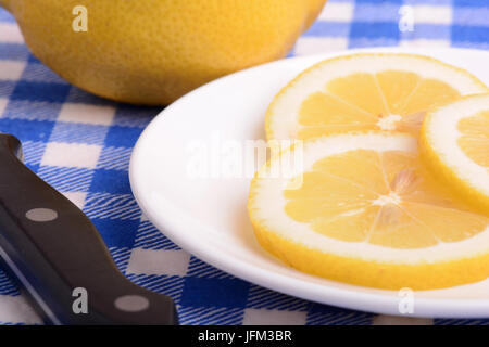 Dimezzate il limone e un coltello su una piastra bianca Foto Stock