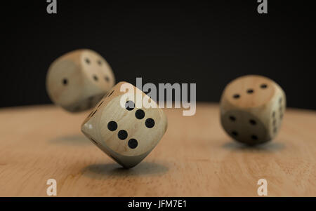 Rotolando giù tre dadi su una scrivania in legno con uno sfondo nero Foto Stock